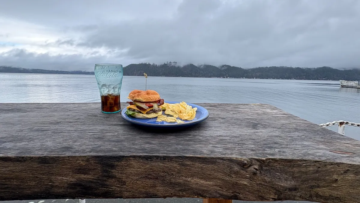 Burger and Coke on a weathered wood table overlooking Hood Canal at Hook & Fork in Union, WA